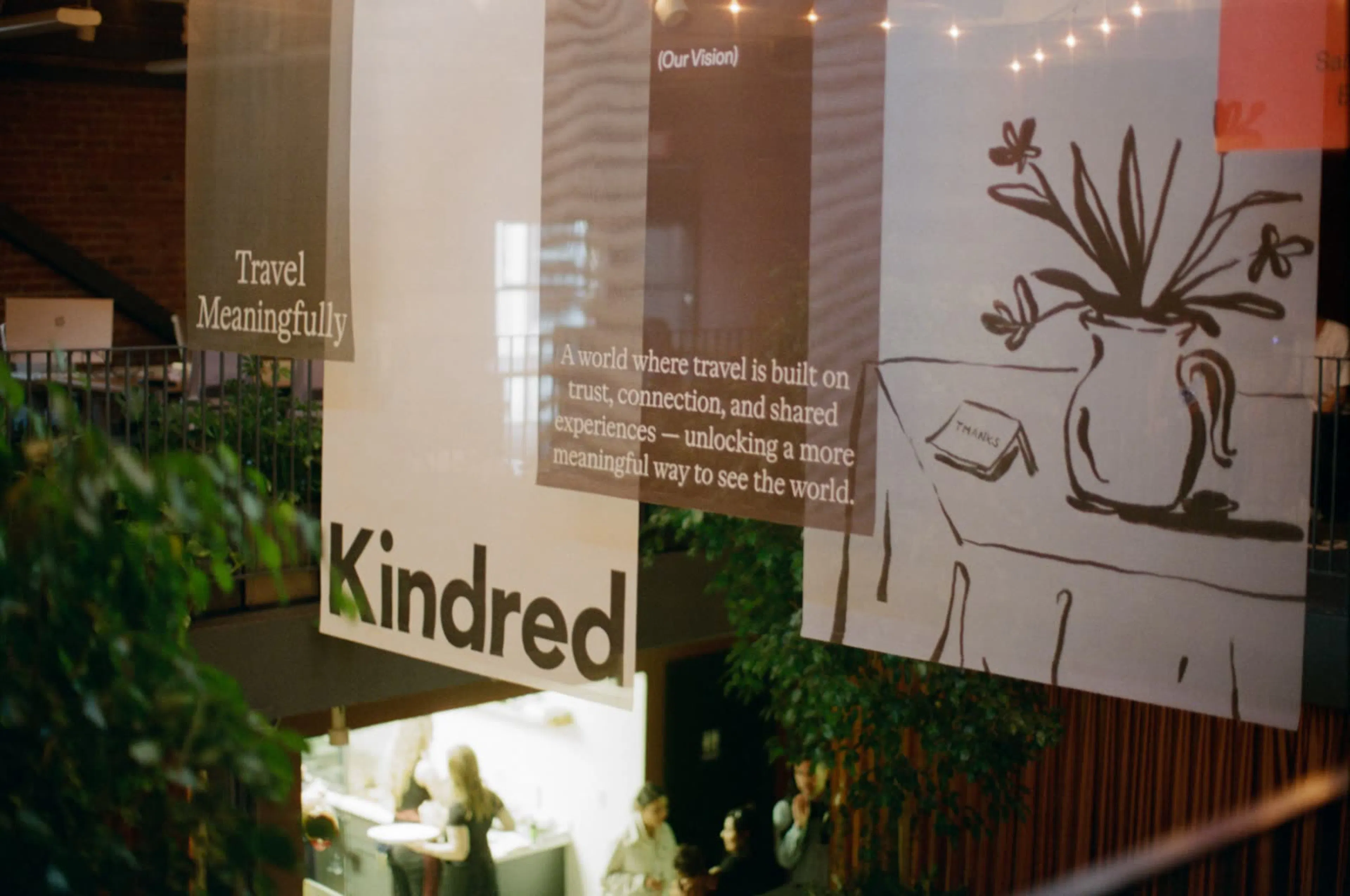 Banners da Kindred com a mensagem “Viaja com significado”, pendurados num espaço de eventos.