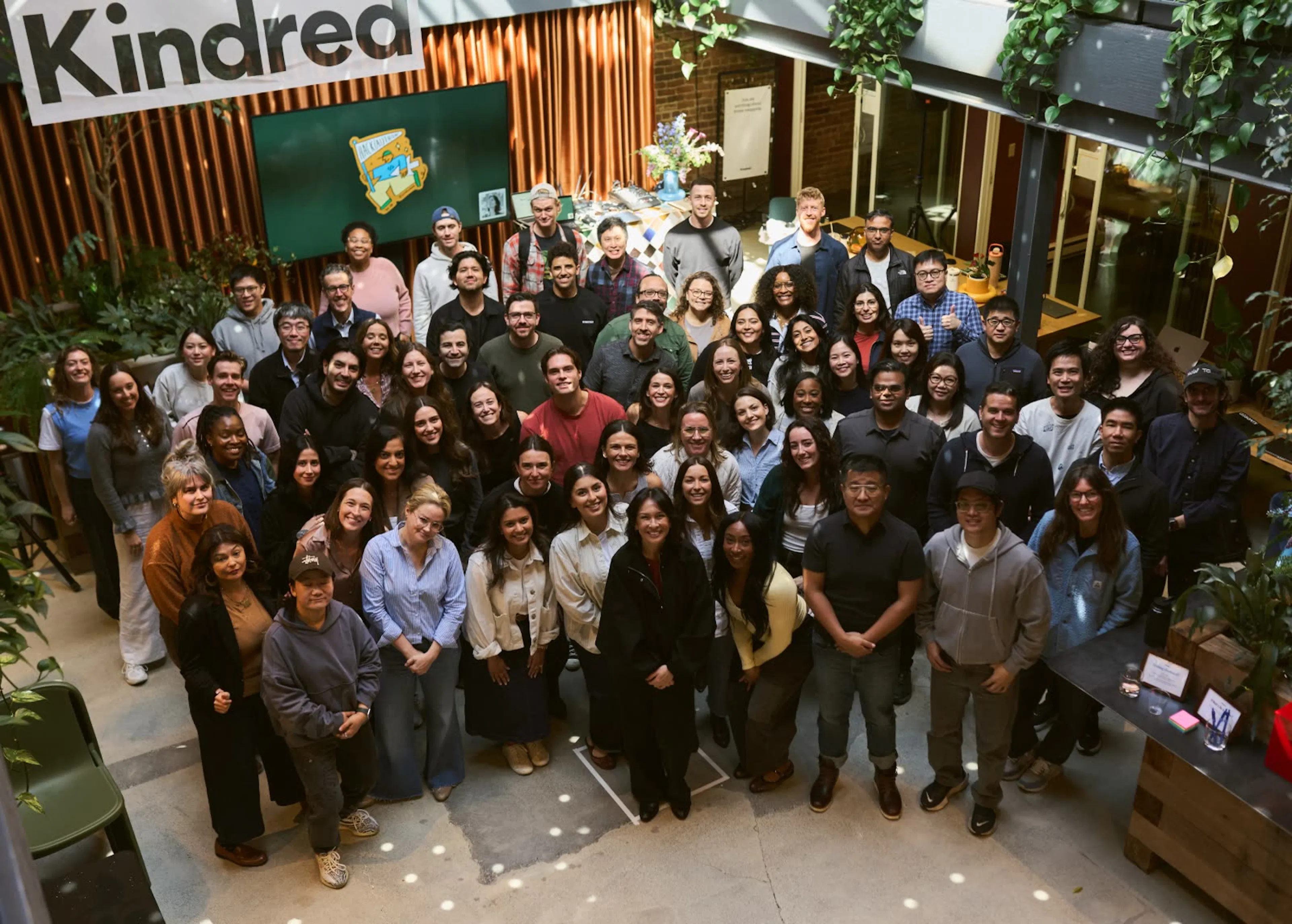 A equipa da Kindred reuniu-se para uma fotografia de grupo sob a faixa da Kindred, durante uma reunião geral.