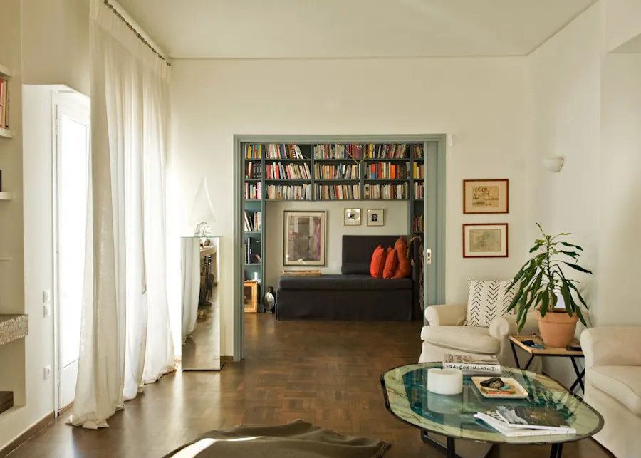 Elegant living space featuring a cozy reading nook with a wall-to-wall bookshelf, warm lighting, and modern furnishings, perfect for Kindred home swapping guests.