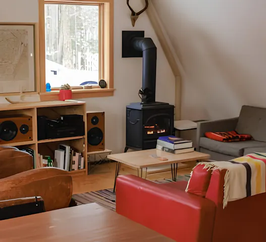 Cozy living room in Barcelona with a wood-burning stove, warm decor, and inviting seating, offered through Kindred home swapping for $13 per night.