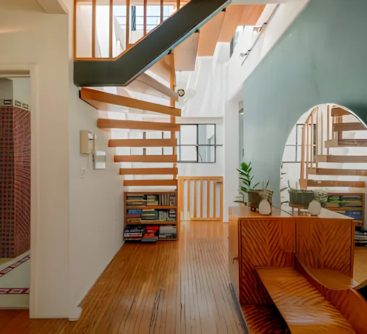 Charming Parisian home with a modern wooden staircase, cozy reading nook, and stylish decor, available through Kindred home swapping for $26 per night.