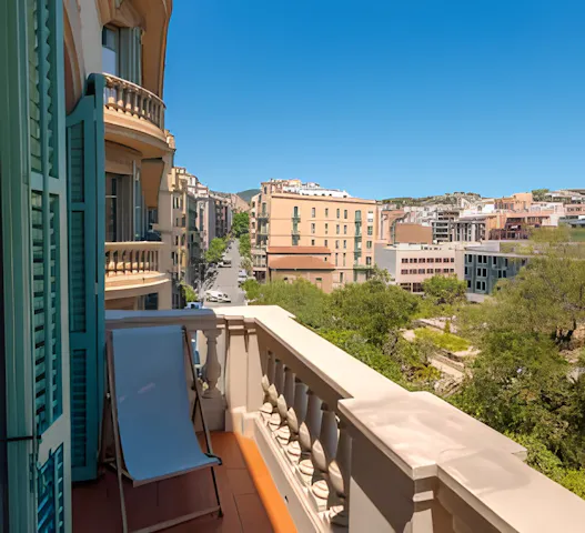 Sunny balcony with city views in Mexico City, featuring a lounge chair and charming architecture, available through Kindred home swapping for $10 per night.