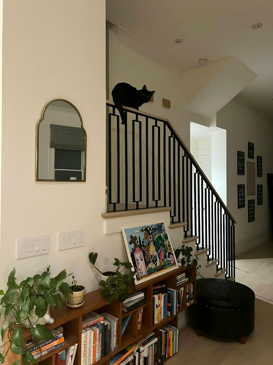 Curious black cat perched on a stair railing in a Kindred home, offering pet-friendly accommodations that allow pets to explore new environments safely. Ideal for pet parents searching for homes that welcome all types of pets, ensuring comfort and adventure for your furry companions.
