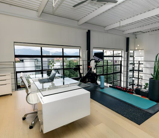 Modern loft workspace in a Kindred home, combining professional work setup with wellness amenities like a fitness area, perfect for maintaining work-life balance on the go.