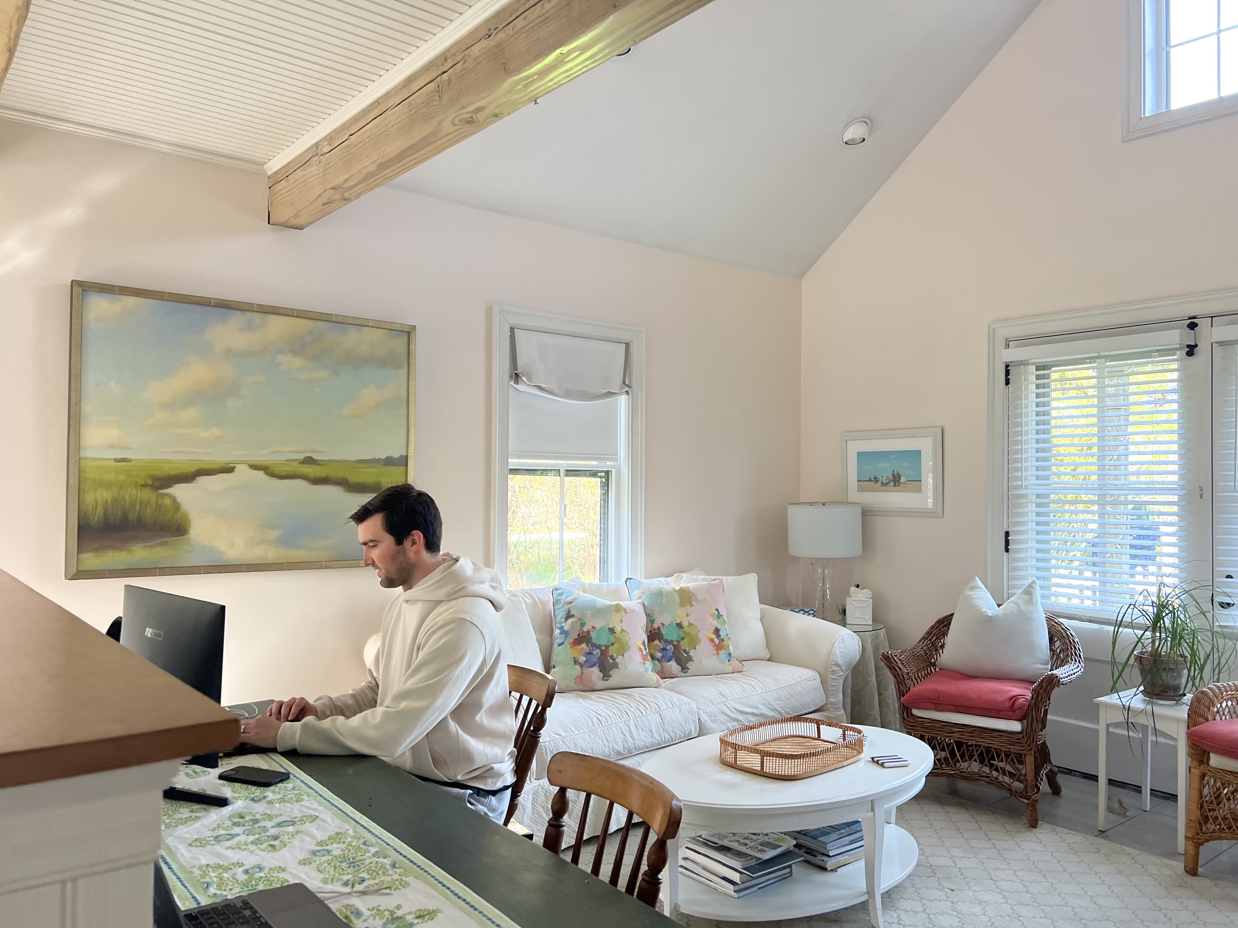Modern home office with a woman working at a large wooden desk, surrounded by plants, art, and a fireplace. An ideal space for remote work, offering creativity, focus, and comfort.