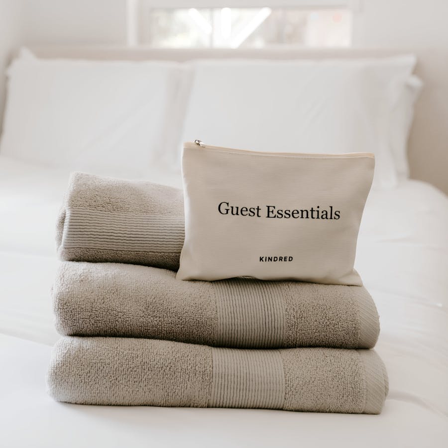 Kindred-branded guest essentials, including linens and toiletries, neatly placed on a fresh bed. Stress-free home swaps with Kindred’s hosting support, perfect for retirees and travelers seeking easy stays and personalized comfort.