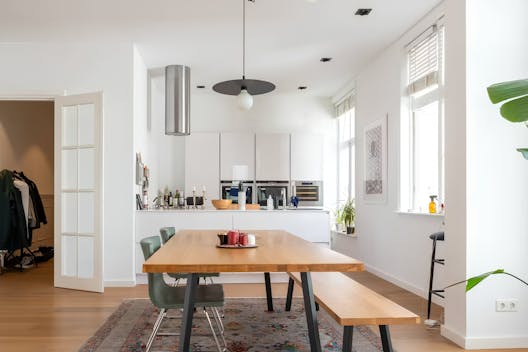 Modern kitchen with a large dining table, perfect for retirees seeking a long-term home swap through Kindred to host family gatherings and enjoy local culinary experiences.
