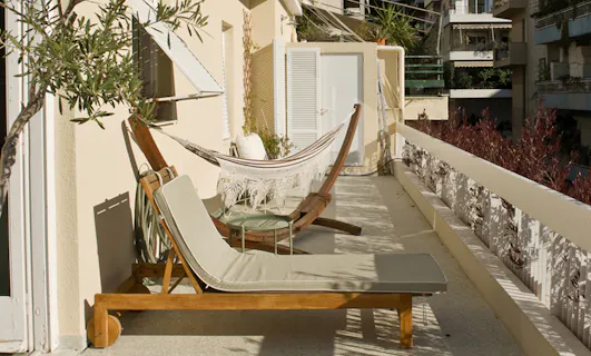 Spacious apartment balcony with hammock and sun loungers, inviting outdoor living during home swaps.
