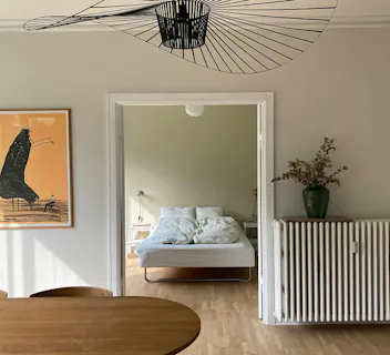Minimalist Scandinavian apartment with bright bedroom and dining area, perfect for home swapping stays.