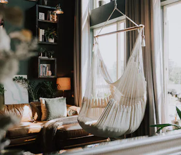 Stylish modern living room with hammock chair and natural light, designed for comfortable home exchanges.